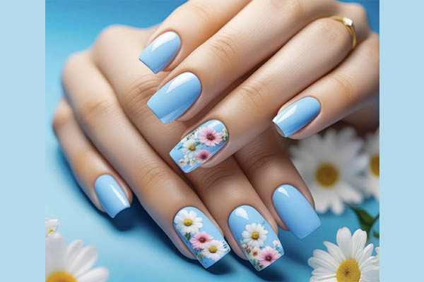 Belles mains aux ongles bleu avec un décor de petites marguerites sur certains ongles.