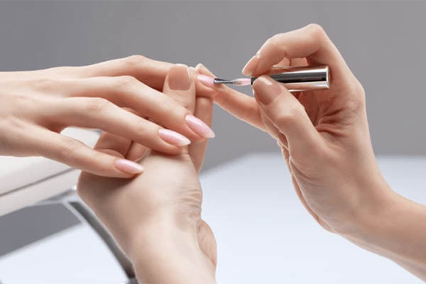 Pose d'un top coat sur ongles parfaitement manucurés et vernis.